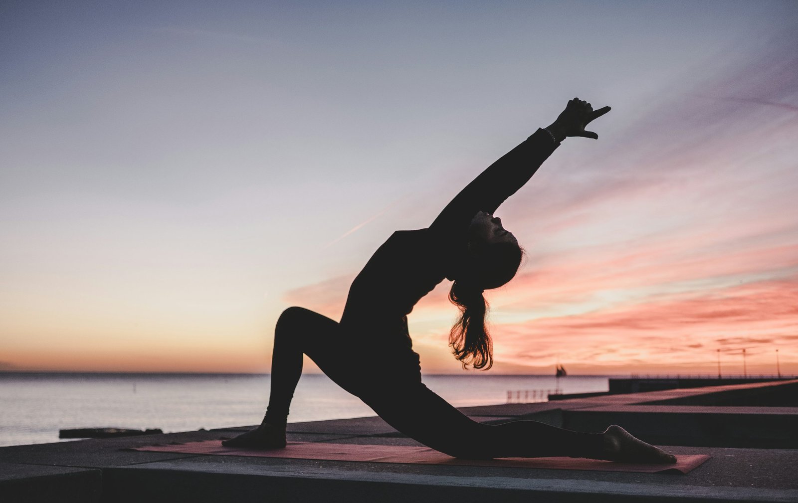 A woman taking a quiet moment during a sunset yoga session