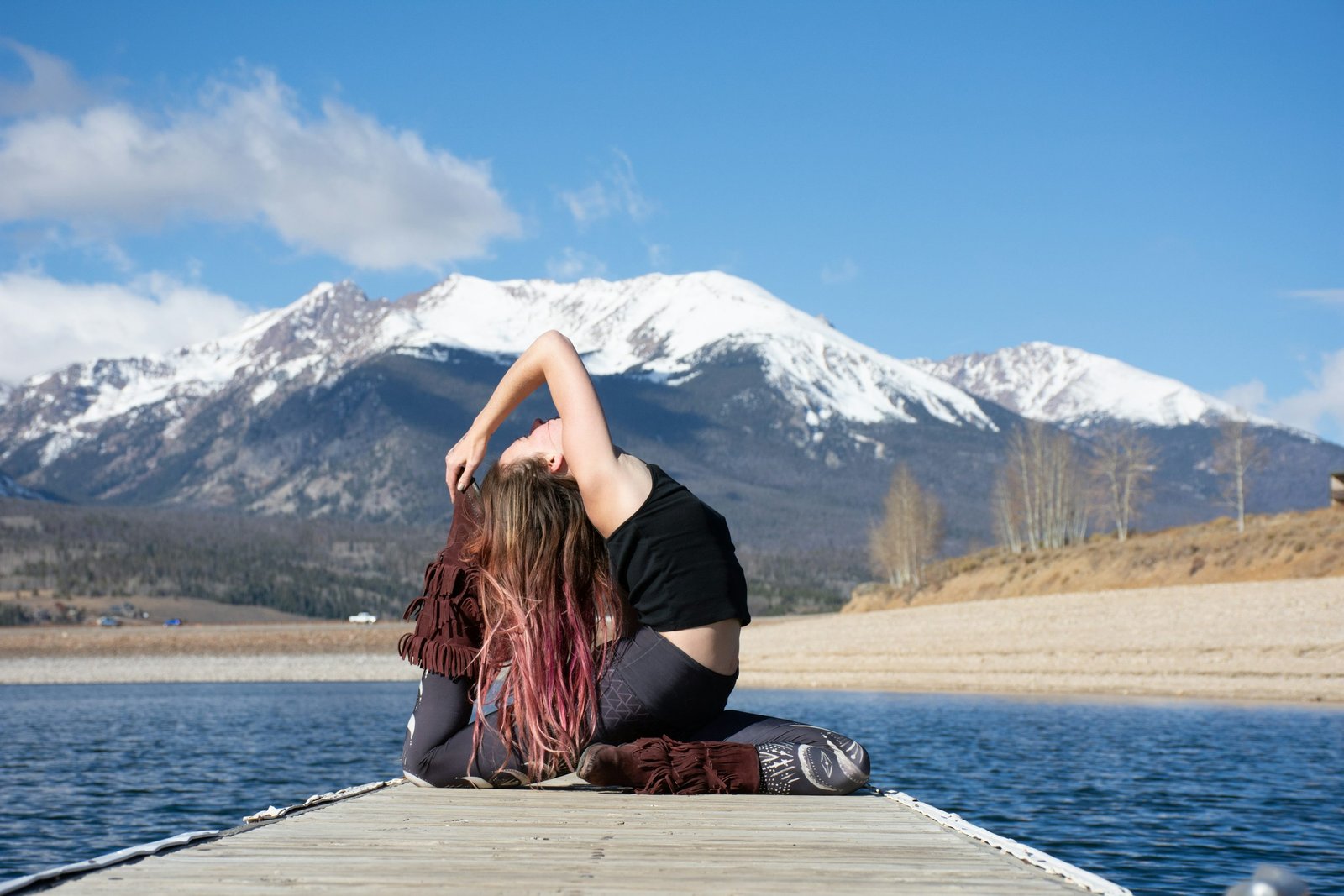 A woman practicing yoga beside a mountain lake